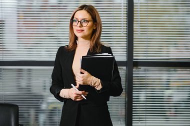 Ofis ortamında gülümseyen genç bir iş kadınının portresi.