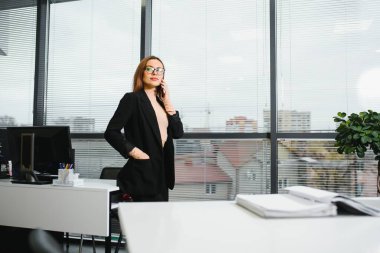 Ofiste kendine güvenen bir iş kadını duruyor.