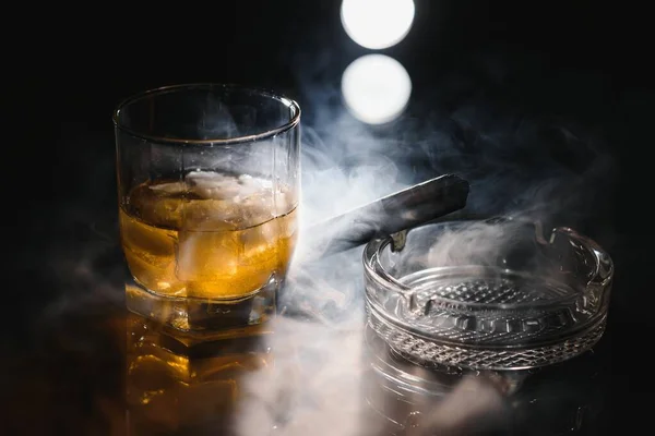 煙と黒スレート上の氷のキューブとシガーとウイスキーやバーボンのガラス — ストック写真