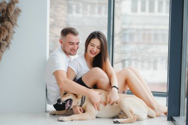 Evde köpeği olan genç bir çift. Genç bir adam ve bir kadın evde köpekle oynuyorlar..