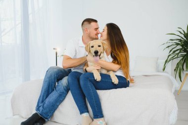 Evde köpeği olan genç bir çift. Genç bir adam ve bir kadın evde köpekle oynuyorlar..