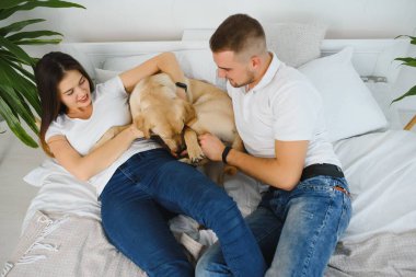 Guy ve kız arkadaşı yatak odasında dinleniyorlar. Mutlu çift evcil hayvanlarına bakar kim oynamak ister