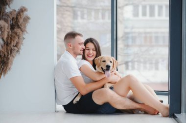 Evde köpeği olan genç bir çift. Genç bir adam ve bir kadın evde köpekle oynuyorlar..