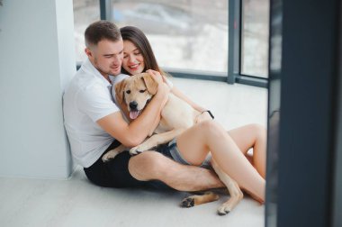 Evde köpeği olan genç bir çift. Genç bir adam ve bir kadın evde köpekle oynuyorlar..