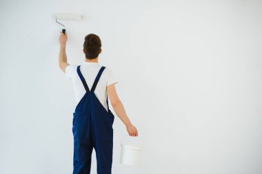 Ressam silindirli bir odanın duvarını boyuyor..