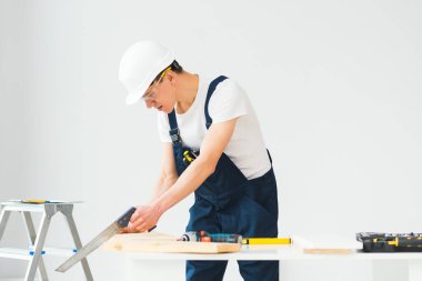 Marangoz apartman tadilatı sırasında beyaz tahtayı kesiyor.