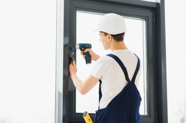 Evdeki oturma odasına plastik pencereler monte eden ya da ayarlayan işçi