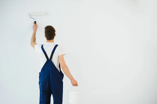 Hombre Joven Mono Azul Pintando Pared Color Blanco Con Rodillo — Foto de Stock