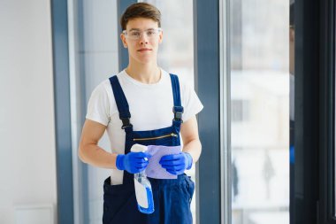 Pencereyi temizleyen ve yeni bir evde gülümseyen adam.