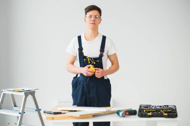 Onarım, inşaat ve inşaat kavramı - arka plandaki yeni evde mutlu gülümseyen erkek işçi ya da gözlüklü müteahhit