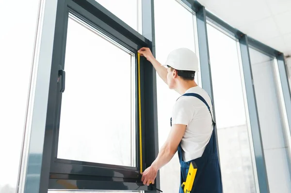 Construction worker installing window in house