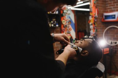 Genç Afro-Amerikalı adam berber dükkanını ziyaret ediyor.