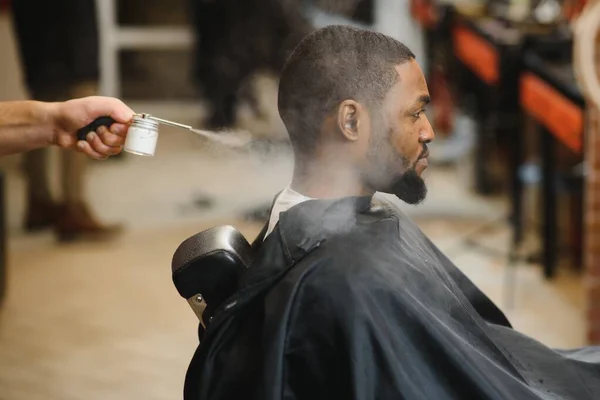 Black man in the barbershop. Cute black man makes a haircut in the African salon. Hair style. Haircut for adults.