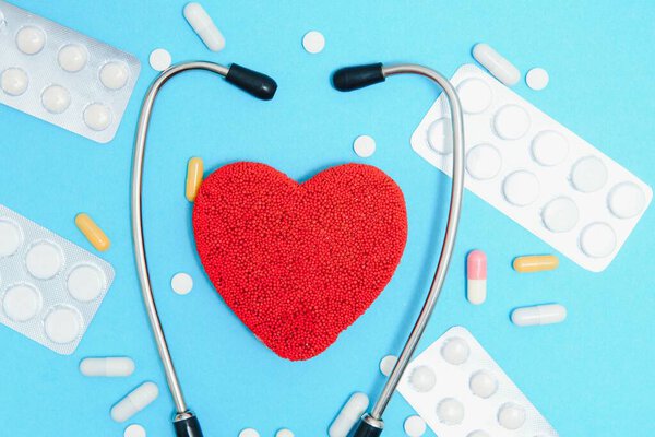 Глобальная концепция здравоохранения: Стильный врач с сердцем на синем фоне. Закрытие красного сердца и стетоскоп на синем фоне. Слушайте сердце с помощью статоскопа.