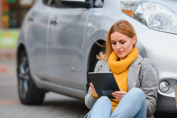 Woman near a rental electric car. Vehicle charged at the charging station.