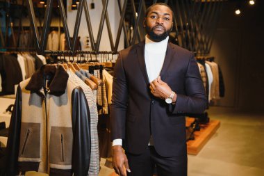 Yakışıklı, iyi giyimli, Afro-Amerikan bir adam klasik erkek giyim mağazasında poz veriyor..