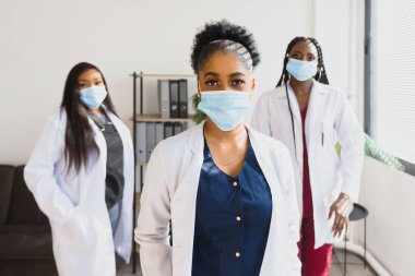 Yüzlerinde koruyucu maskeler olan bir grup Afrikalı Amerikalı kadın doktor.