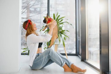 Güzel sarışın kadın evde köpeğiyle oynuyor, gülümsüyor. Mutluluk.