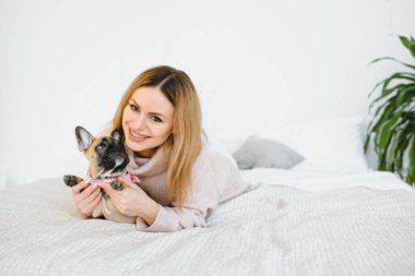 Evde köpeğiyle oynayan genç bir kadın.