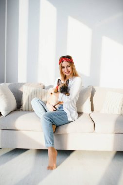 Evde köpeğiyle oynayan genç bir kadın.