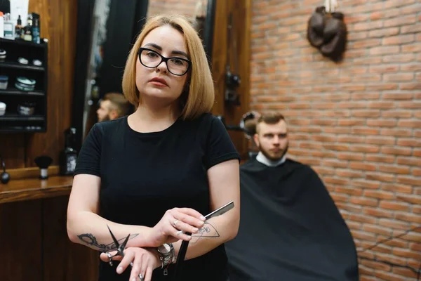 Portrait of fashion woman barber hairstylist with scissors in hand in the barbershop