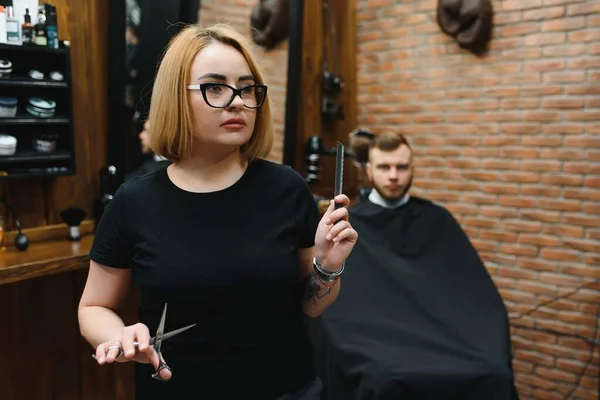 Portrait of fashion woman barber hairstylist with scissors in hand in the barbershop