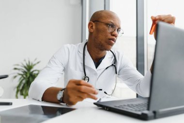 Beyaz önlüklü Afrikalı Amerikalı bilim adamı deney tüpünü ayırıcı ve laboratuvar araştırmacısı konseptiyle inceliyor.