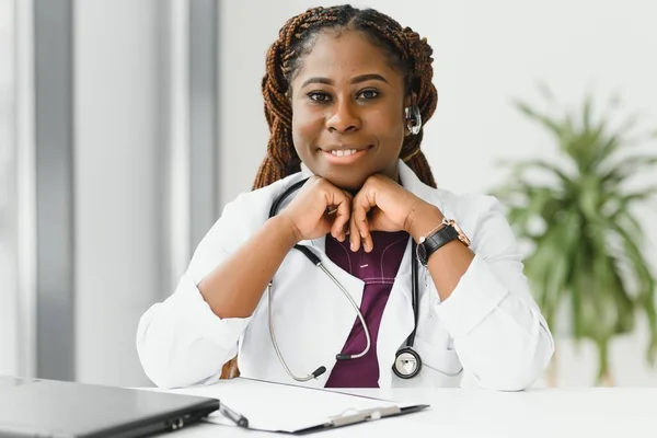 medicine, online service and healthcare concept - happy smiling african american female doctor or nurse with headset and laptop having conference or video call at hospital