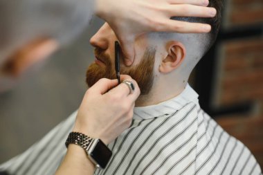 Berberin keskin bir jiletle traş edişının yakın çekimi..