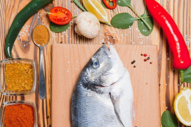 Limon, biber, domates ve ahşap zemin üzerinde kopya alanı olan çeşitli baharatlarla birlikte taze çiğ dorado balığı..