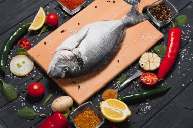 Çiğ balık pişirme ve malzemeler. Dorado, limon, otlar ve baharatlar. Masada kopyalama alanı olan üst görünüm