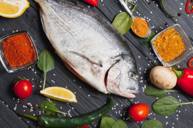 Limon, biber, domates ve ahşap zemin üzerinde kopya alanı olan çeşitli baharatlarla birlikte taze çiğ dorado balığı..