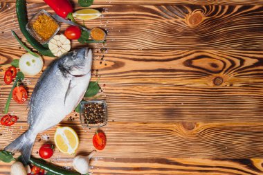 Taze çiğ dorado balığı. Çipura, ahşap bir tahtanın üzerinde, otlar, tuz ve baharatla birlikte. Dorado ve masada yemek pişirmek için malzemeler. Yakın plan.
