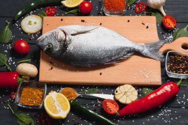 Limon, biber, domates ve ahşap zemin üzerinde kopya alanı olan çeşitli baharatlarla birlikte taze çiğ dorado balığı..