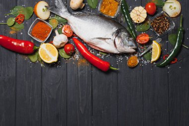 Limon, biber, domates ve ahşap zemin üzerinde kopya alanı olan çeşitli baharatlarla birlikte taze çiğ dorado balığı..