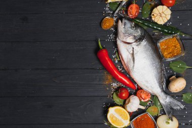 Limon, biber, domates ve ahşap zemin üzerinde kopya alanı olan çeşitli baharatlarla birlikte taze çiğ dorado balığı..