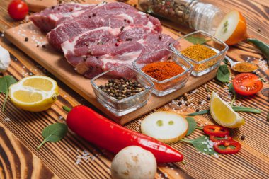 Baharatlı çiğ domuz eti ve ahşap masada sebze.