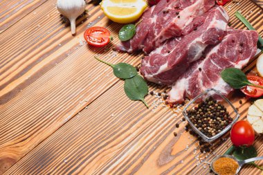 Mutfak masasındaki ahşap kesme tahtasında çiğ domuz eti. Biftek pişirmek için. Kavrulmuş ya da baharatla kızartılmış.