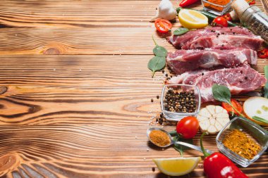 Baharatlı çiğ domuz eti ve ahşap masada sebze.