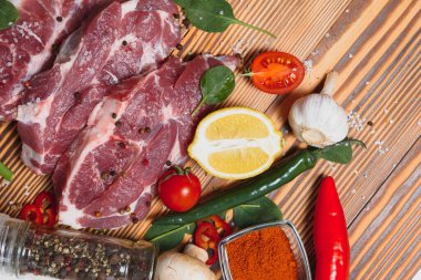 Mutfak masasındaki ahşap kesme tahtasında çiğ domuz eti. Biftek pişirmek için. Kavrulmuş ya da baharatla kızartılmış.