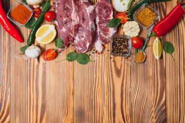 Baharatlı çiğ domuz eti ve ahşap masada sebze.