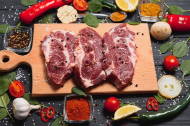 Baharatlı çiğ domuz eti ve ahşap masada sebze.