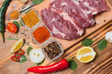 Mutfak masasındaki ahşap kesme tahtasında çiğ domuz eti. Biftek pişirmek için. Kavrulmuş ya da baharatla kızartılmış.