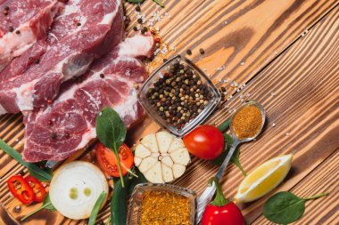 Baharatlı çiğ domuz eti ve ahşap masada sebze.