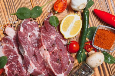 Baharatlı çiğ domuz eti ve ahşap masada sebze.