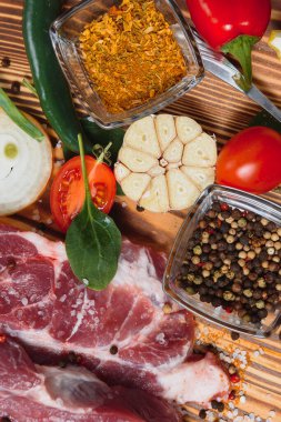 Mutfak masasındaki ahşap kesme tahtasında çiğ domuz eti. Biftek pişirmek için. Kavrulmuş ya da baharatla kızartılmış.
