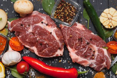 Baharatlı çiğ domuz eti ve ahşap masada sebze.