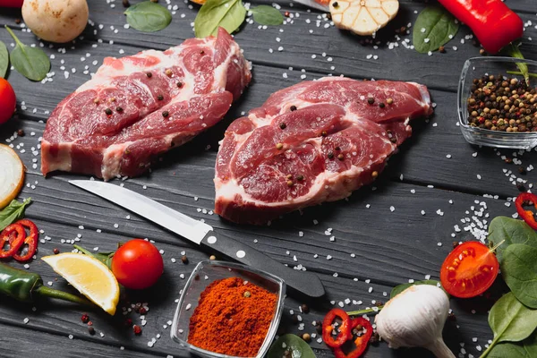 Mutfak masasındaki ahşap kesme tahtasında çiğ domuz eti. Biftek pişirmek için. Kavrulmuş ya da baharatla kızartılmış.
