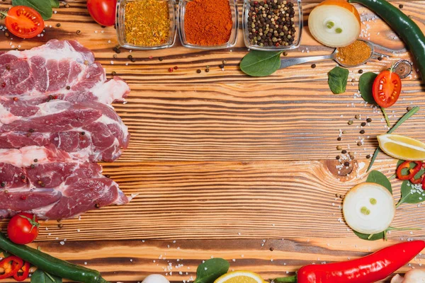Mutfak masasındaki ahşap kesme tahtasında çiğ domuz eti. Biftek pişirmek için. Kavrulmuş ya da baharatla kızartılmış.