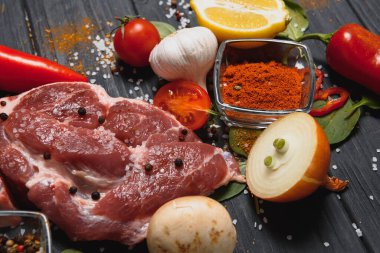 Mutfak masasındaki ahşap kesme tahtasında çiğ domuz eti. Biftek pişirmek için. Kavrulmuş ya da baharatla kızartılmış.